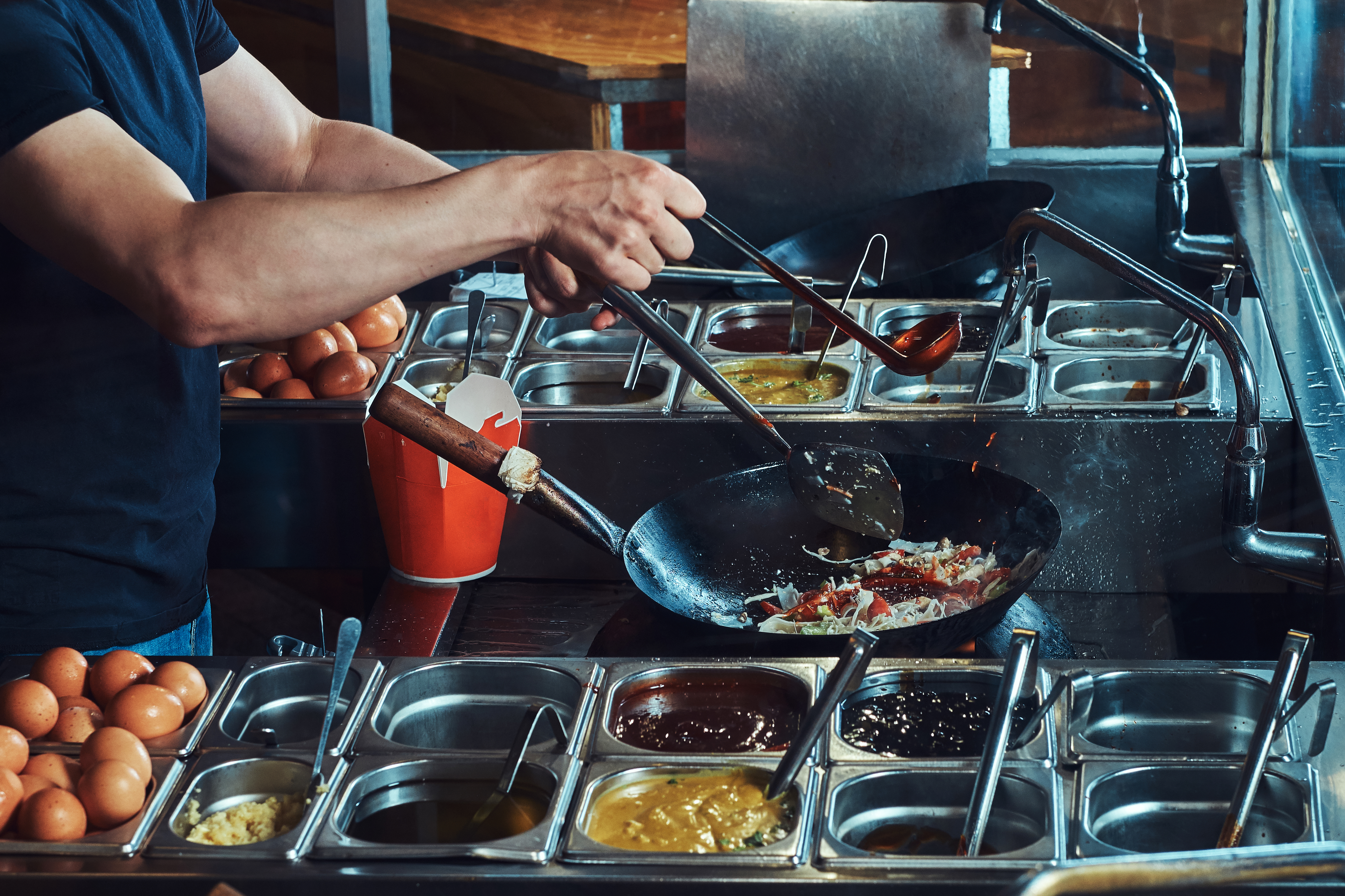 An image of perpared food in mise en place around a person cooking in a skillet.